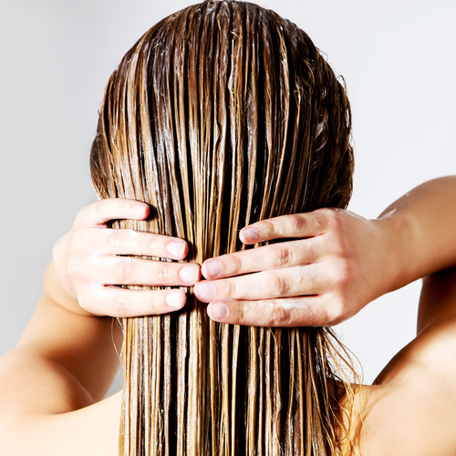 Woman applying hair conditioner. Isolated on white.